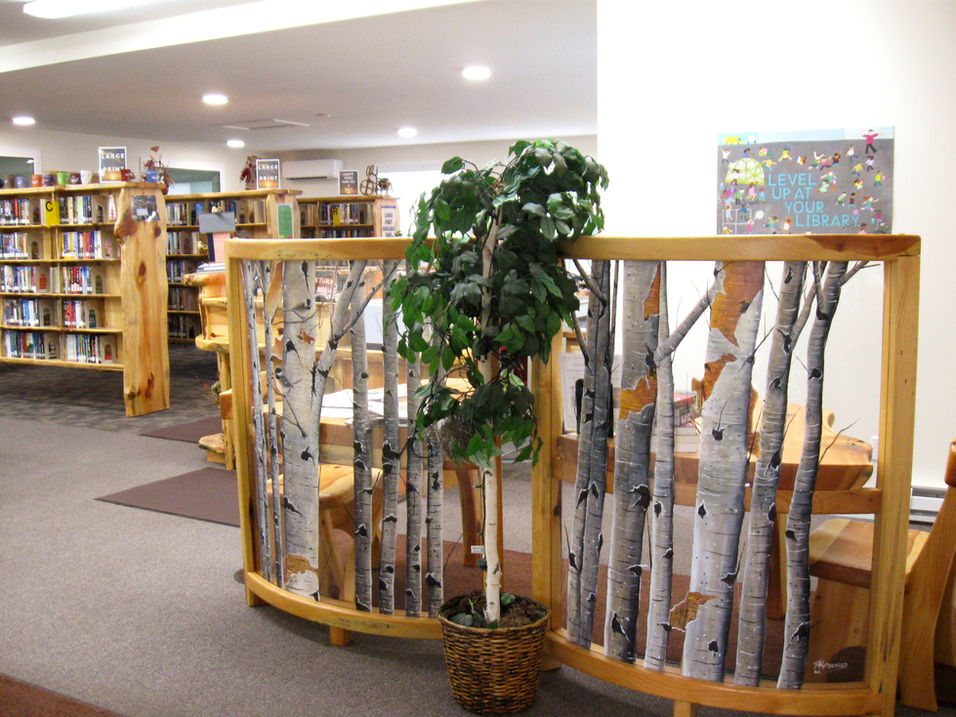 Wooden birch tree design inside a library with bookshelves and seating area