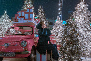 Chica sentada entre árboles de navidad