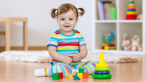 A girl toddler in colorful striped pajamas playing with blocks