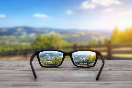 a goffy landscape in the distant background and a pair of glasses in the foreground that shows a clear image in the lenses.