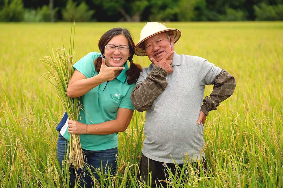 一位戴著斗笠的農夫與一位年輕女性站在稻田中,兩人並肩微笑擺姿勢,展現代代傳承的稻米產業情感與活力。