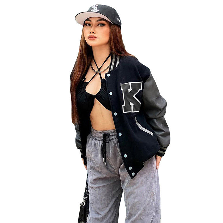Thumbnail:  young women modeling a black varsity-style jacket with a large "K" patch, paired with loose grey pants, sneakers, and baseball caps. Each model holds a small handbag, posing against a white background.