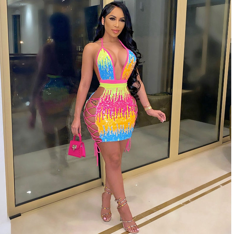 縮圖：Woman wearing a sleeveless, deep V-neck mini dress with multicolor sequins in pink, yellow, and blue tones, holding a pink handbag and posing indoors.