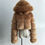 Thumbnail: Brown cropped faux fur puffer coat with hood displayed on a mannequin torso against a plain background.