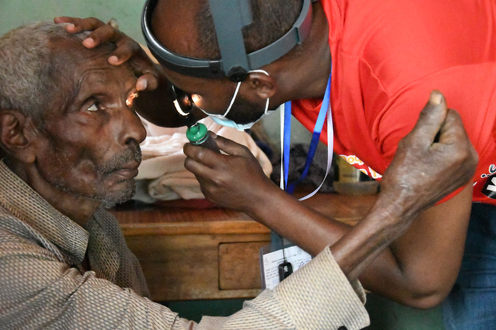Eye doctor examining an older man's eye with a headlamp
