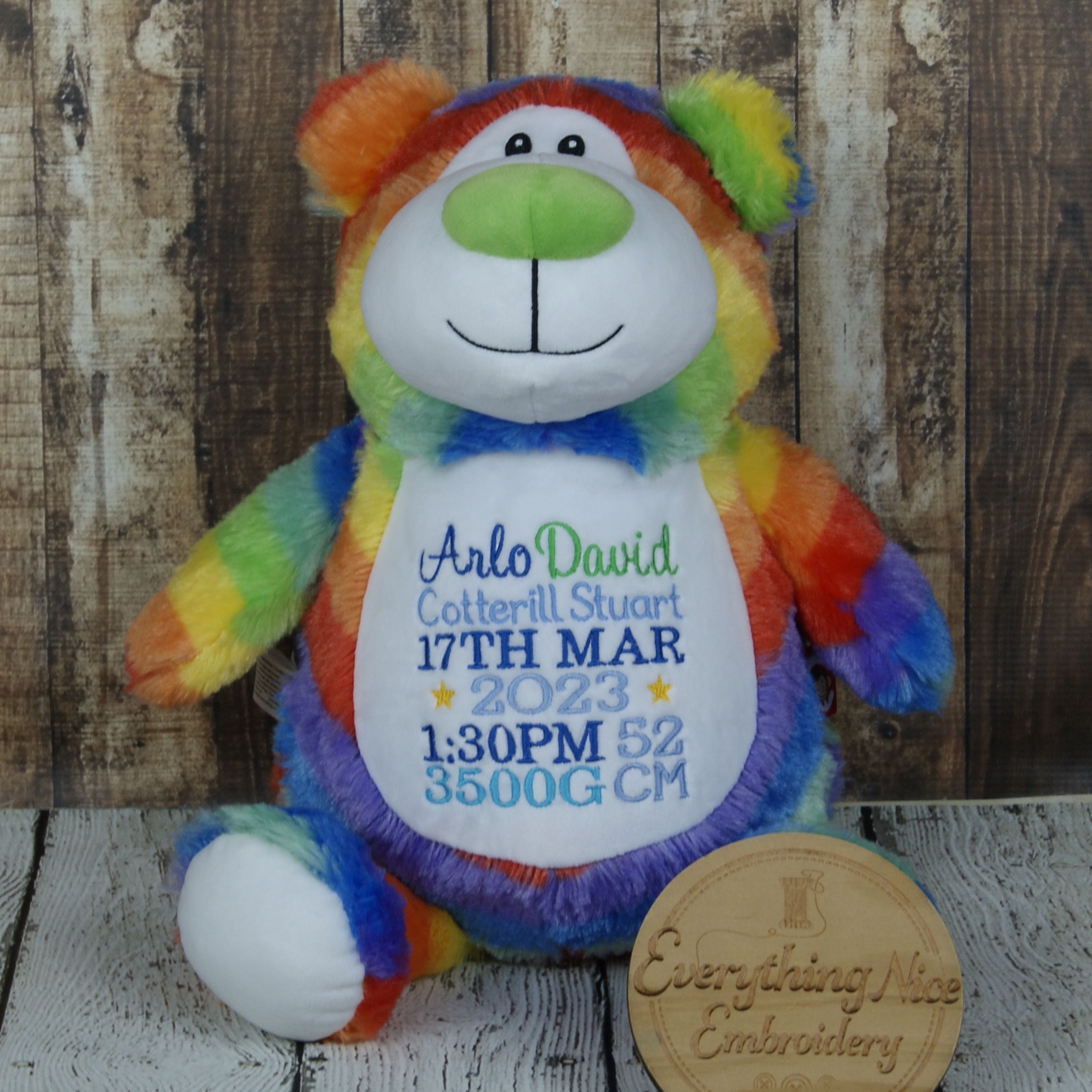 Rainbow teddy bear custom embroidered with matching colorful baby birth announcement details.