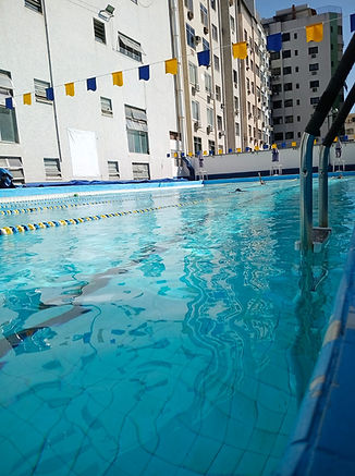 Vista lateral da piscina semiolÃmpica com raias e bandeirolas azuis e amarelas.