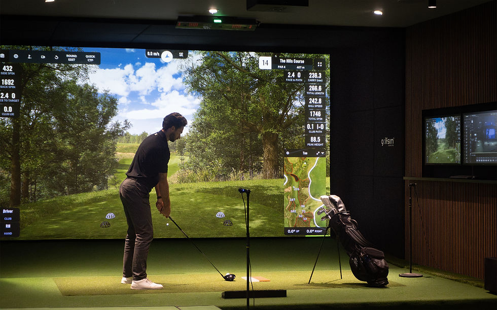 Golfer hitting a shot in a premium indoor golf simulator with Uneekor launch monitor and large projection screen