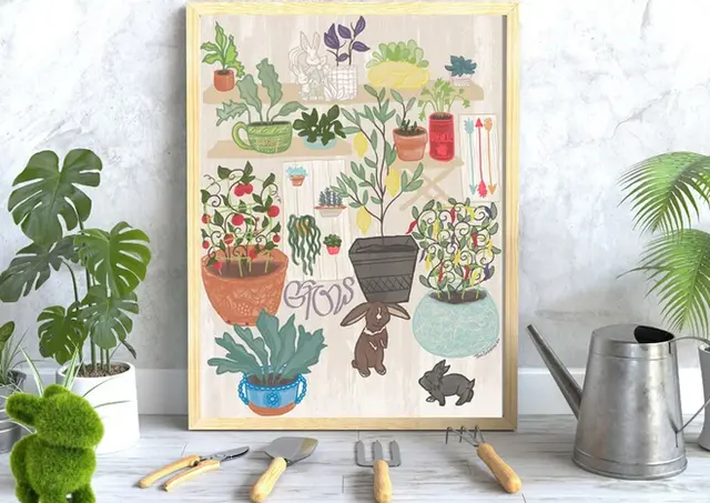 A illustrated picture of two bunnies in a greenhouse surrounded by potted plants framed sitting on a white marbel table next to gardening tools, a watering can, and some real leafy house plants.