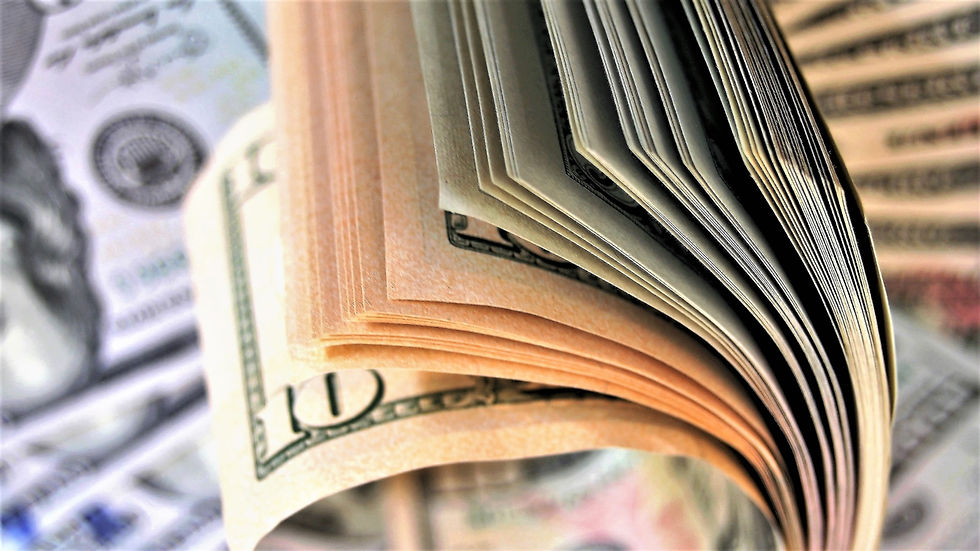 Close-up of a fanned stack of U.S. dollar bills, focusing on the intricate green details, set against a blurred background of more bills.