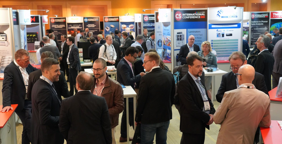Crowded exhibition hall at PIC International 2024 in Brussels with professionals networking and visiting booths from photonics and semiconductor companies.