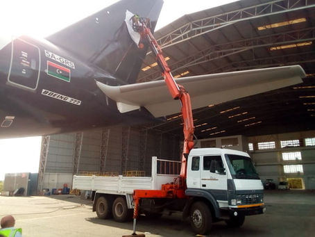 a self loader truck with a crane lifting a Boeing