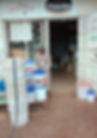 Man sitting outside a shop labeled "Happy Feeds Chachu", surrounded by stacks of white buckets and sacks, against a rustic, earthy background.