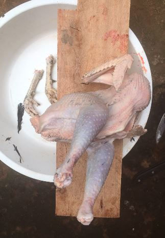 Raw chicken pieces on a white plate and wooden board, viewed from above, with a rustic kitchen prep scene.