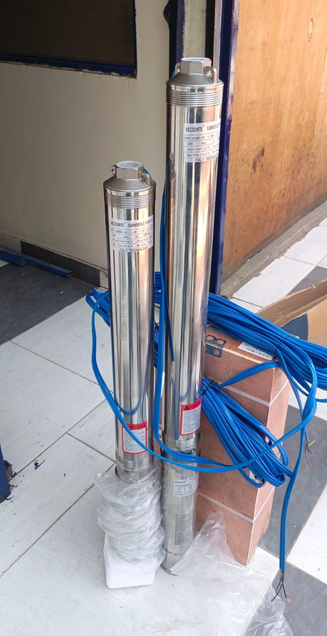 Two shiny metal submersible pumps with blue cables, labeled "VECOUNTE," stand on white tiles near a door. Brown box in the background.