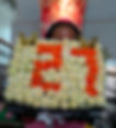 Person holding a floral arrangement of white and orange roses forming "29", with gold butterflies. Background features floral-themed decor.