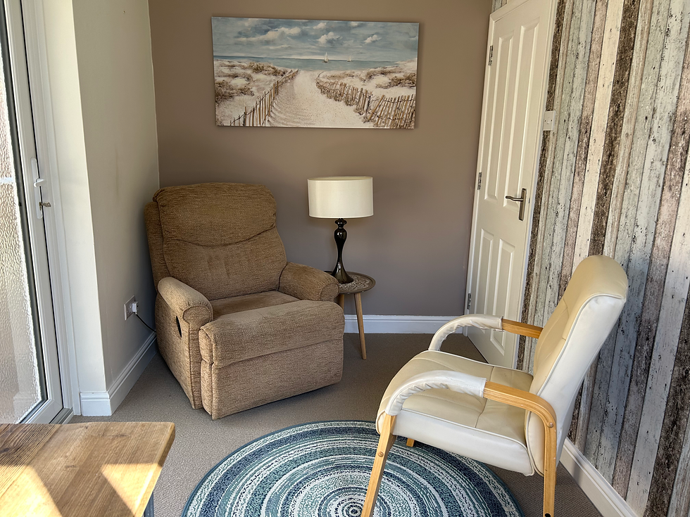 Therapy room with brown recliner, cream armchair, and beach painting