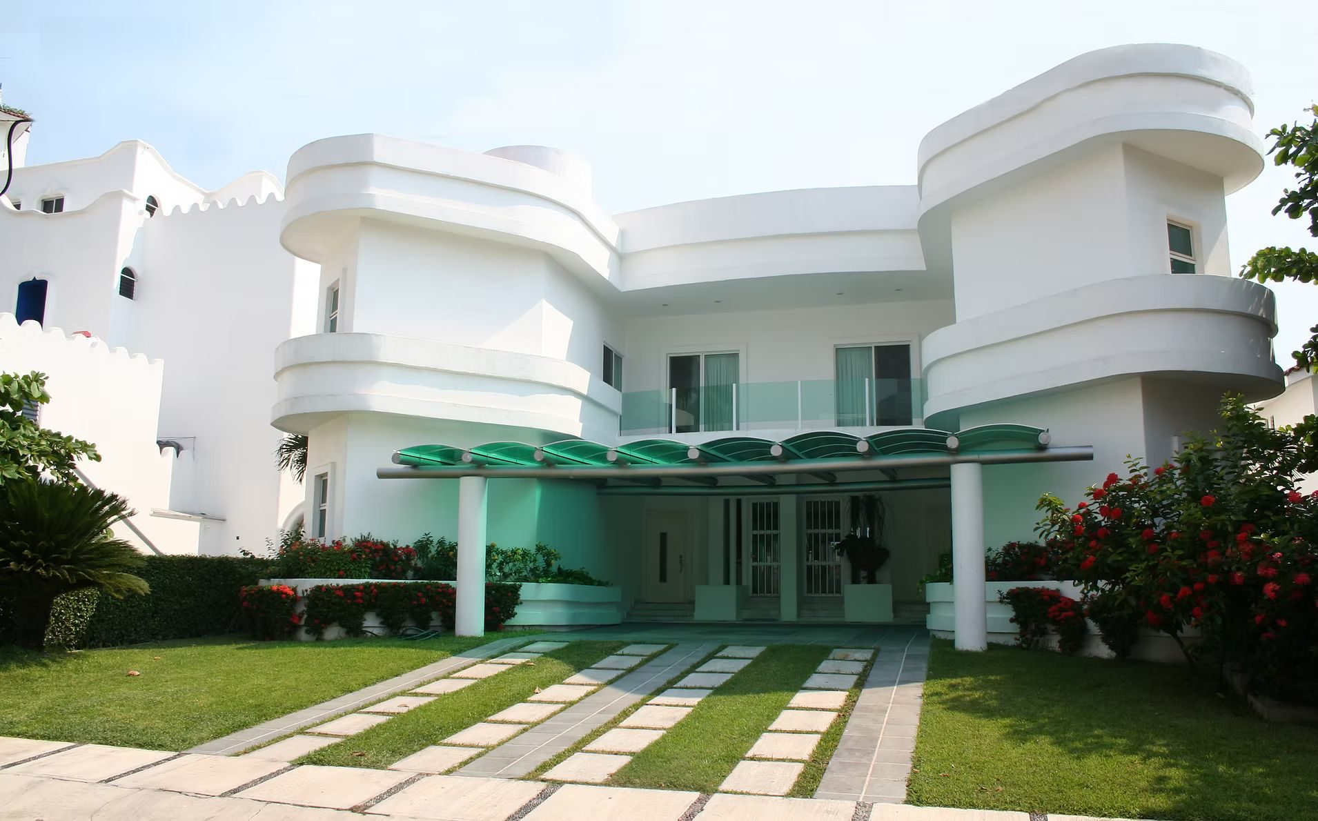 A modern white coastal home with a landscaped walkway leading to the entrance