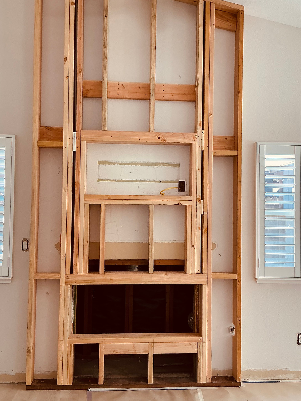 In-progress fireplace remodel with exposed wood framing from floor to ceiling as part of a whole home renovation.