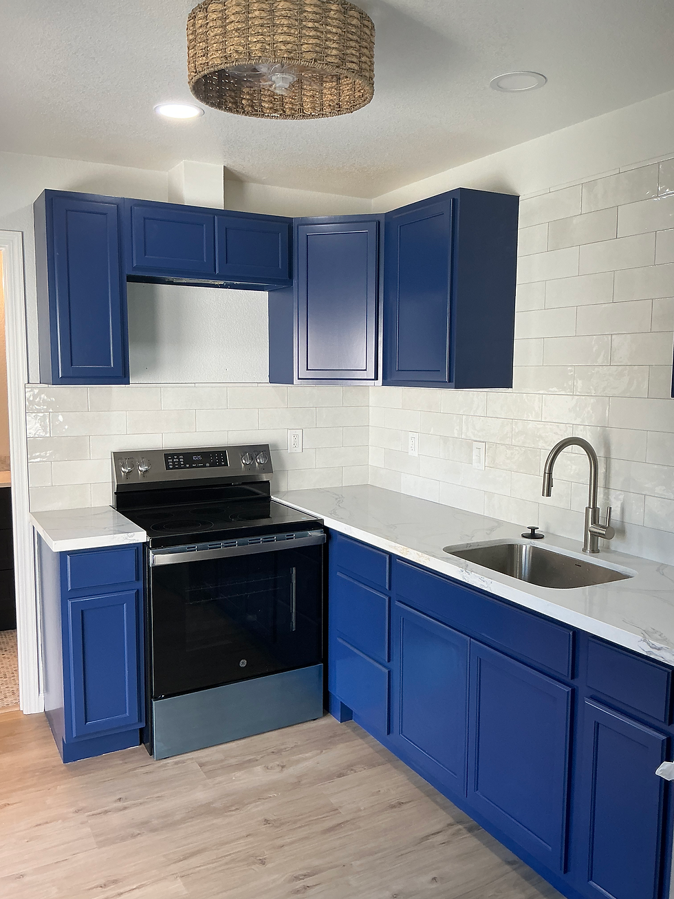 Vibrant blue kitchen cabinets paired with stain-resistant white countertops and a tile backsplash for easy cleaning after heavy cooking.