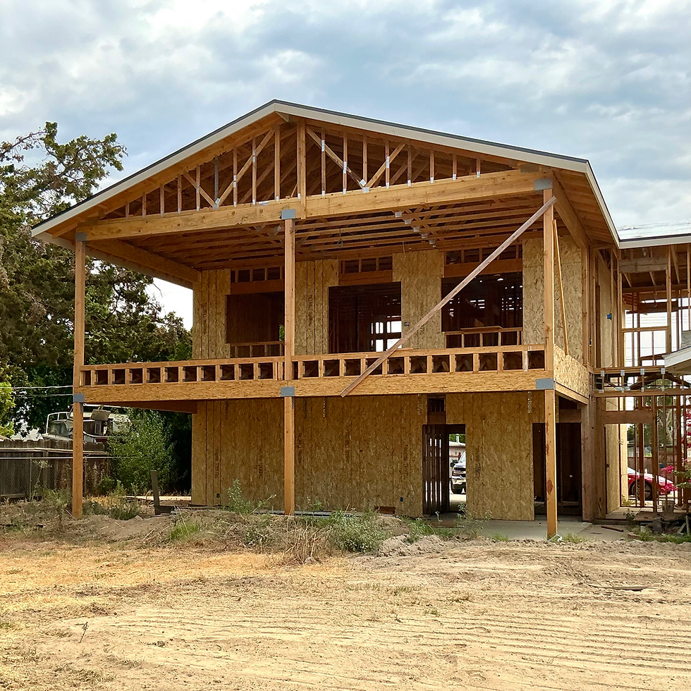 Wood framing and exterior sheathing under construction for a garage with a covered deck patio and second-story ADU addition.