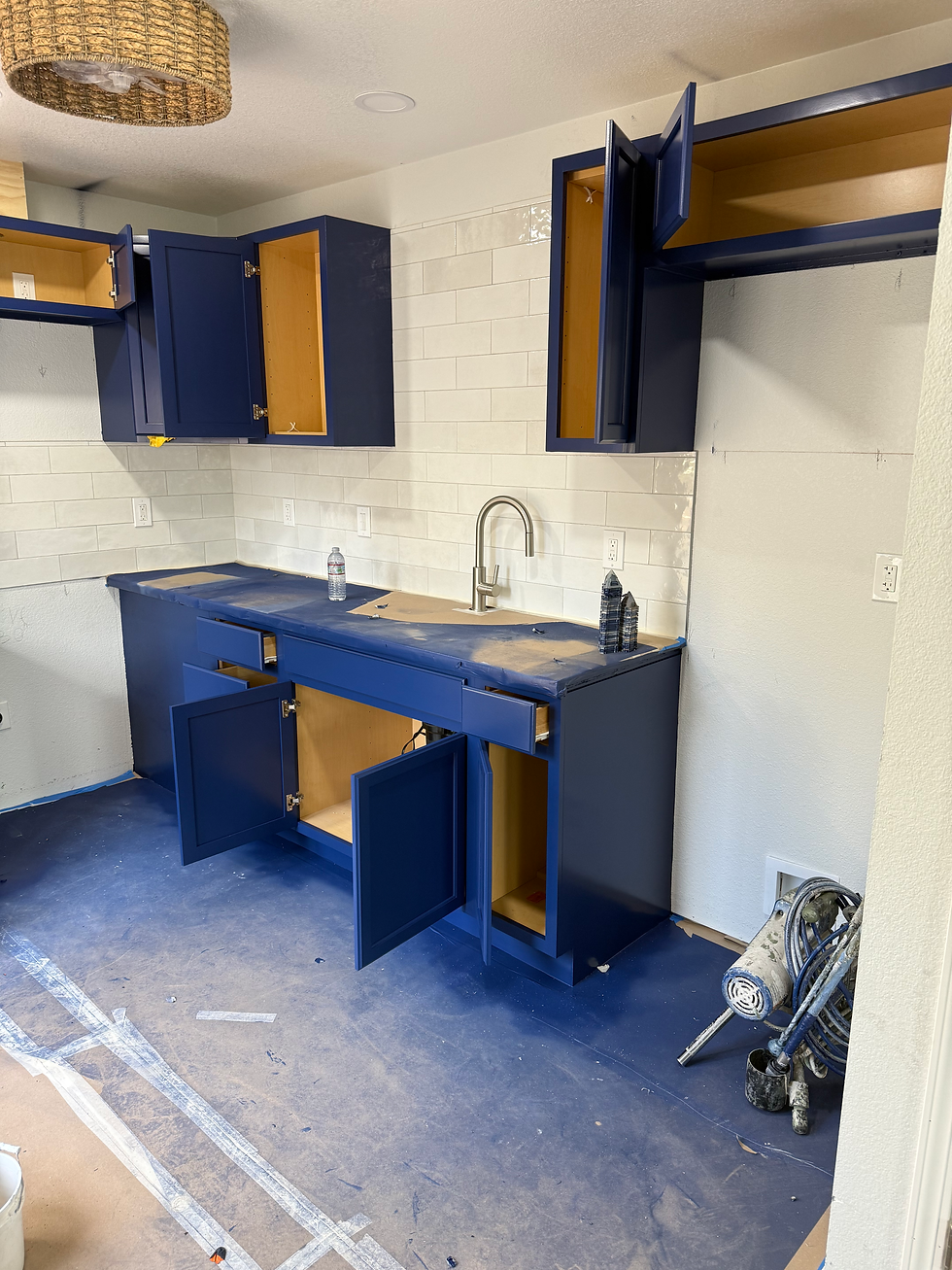 Kitchen remodel in progress featuring deep blue cabinets, a white subway tile backsplash, a stainless steel faucet, and protected floors and countertops.