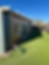Exterior view of an enclosed patio addition with windows, sliding glass door, siding, and backyard lawn.