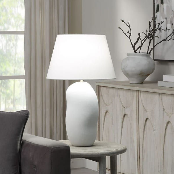 Lampe en céramique blanc mat texturée déposé sur une table d'appoint dans un salon