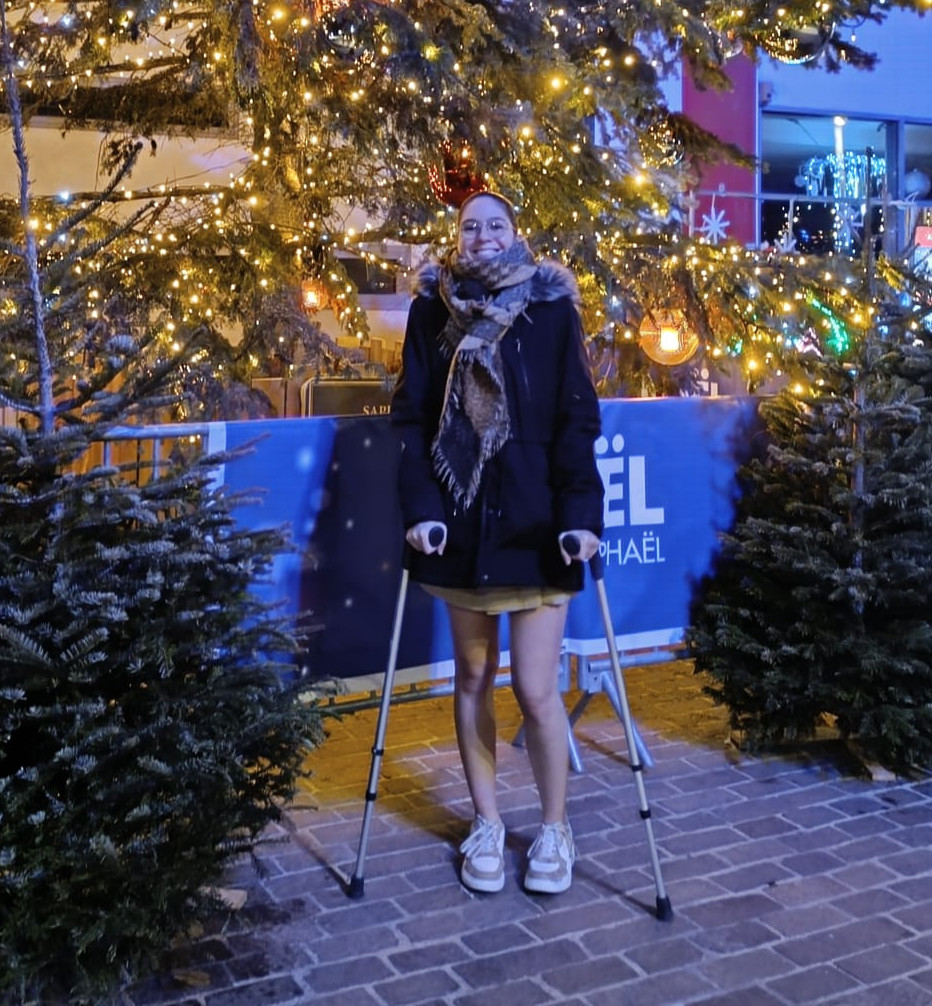 Une personne devant un grand sapin de Noël illuminé.