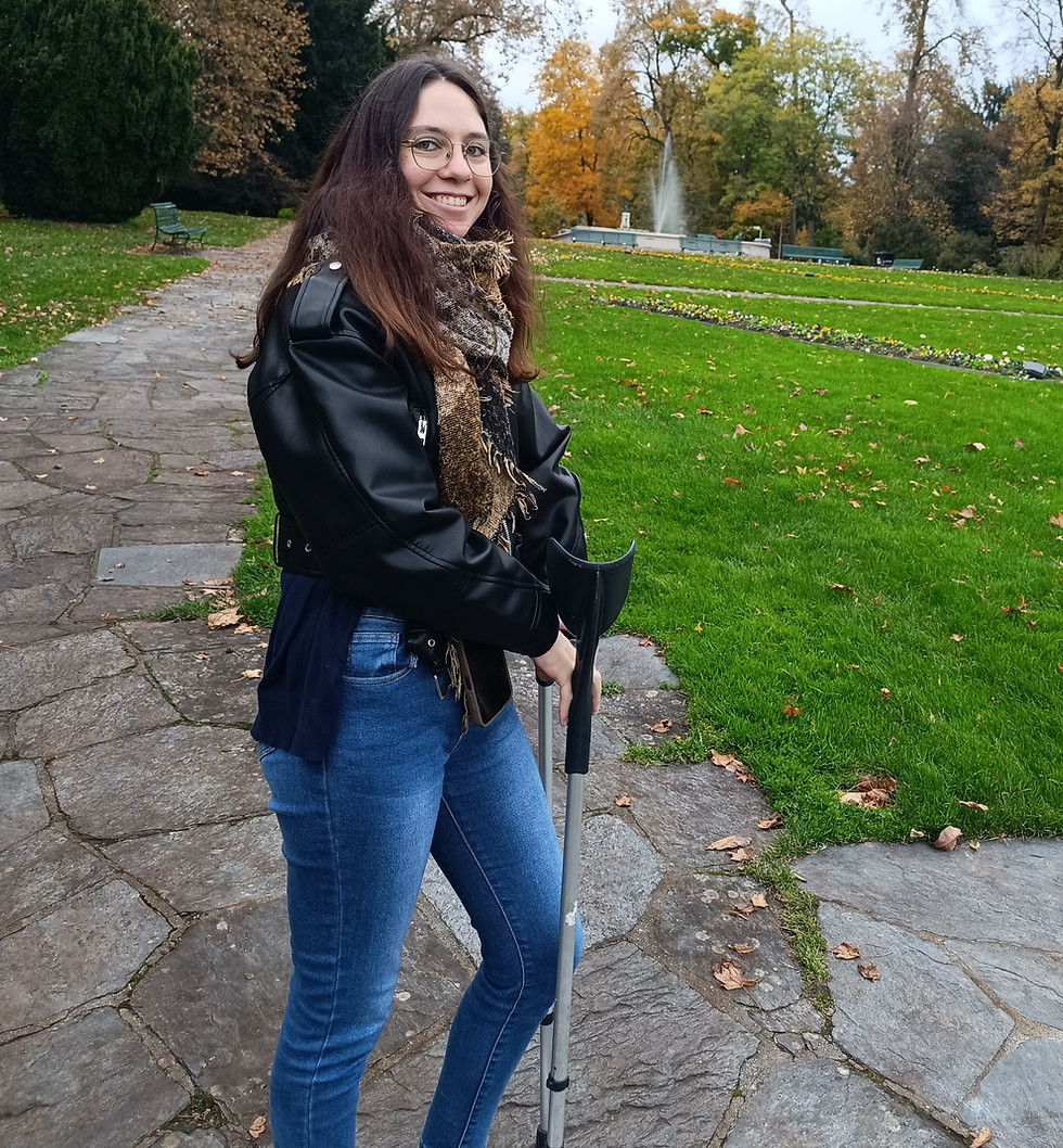 Femme souriante avec béquille sur chemin de pierre, parc automnal.