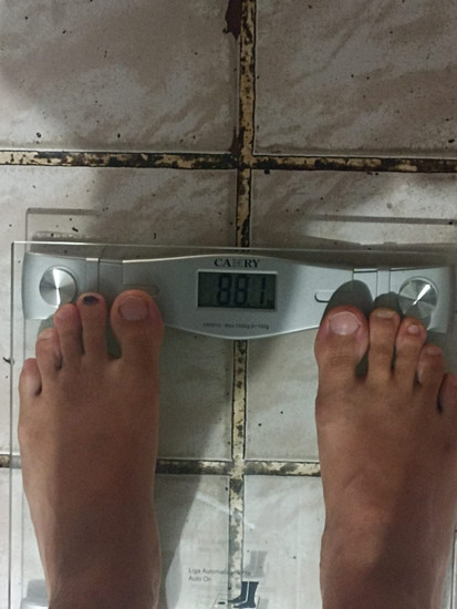 um homem vendo seu peso em uma balança