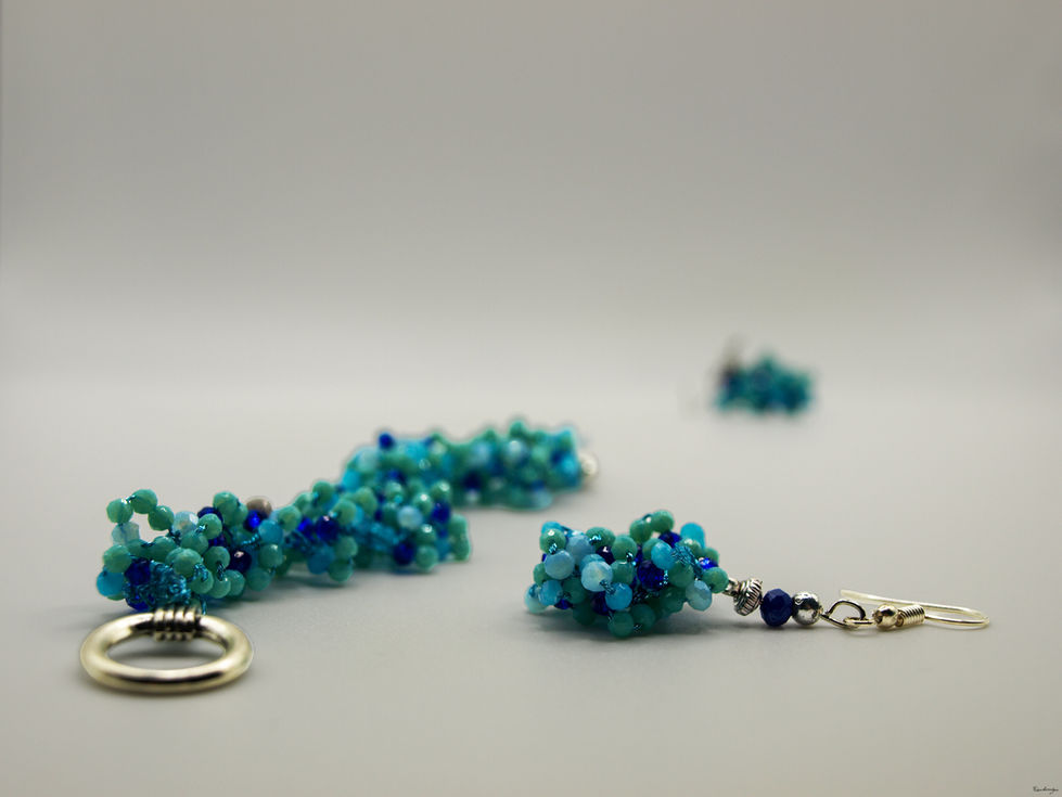 Braccialetto e orecchini a grappolo, con perline di colore azzuro, celeste, e blu, di 2.5 e 3.0 mm. Nell'orecchino, le perline sono chiuse da due perle di colore blu scuro, e color argento.