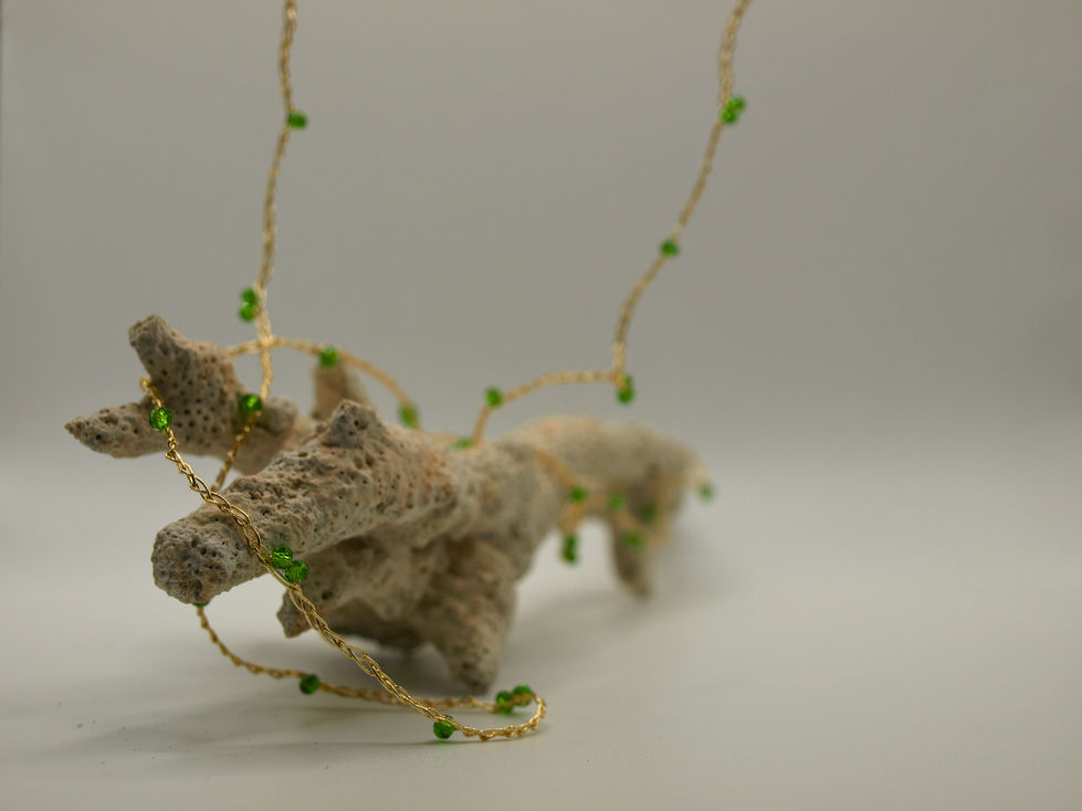 Collana lunga, anche avvolgibile a due o tre fili, con palline verdi di 3 mm, infilate su catenella di filo dorato, a spazi di dieci punti.