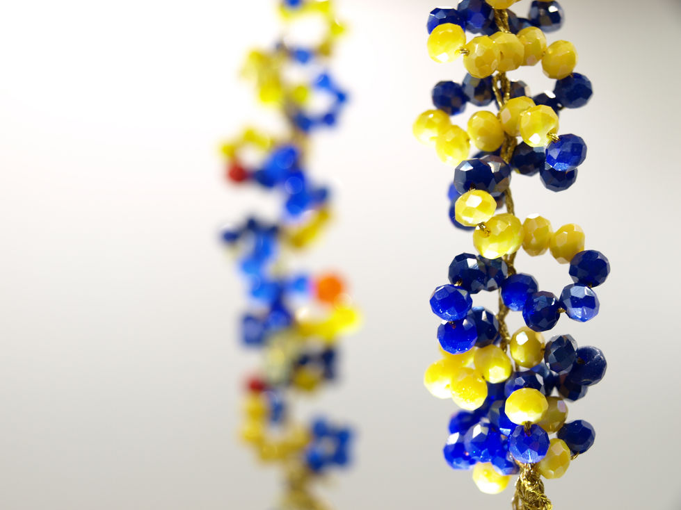 Collana girocollo con gruppi di cinque perline, di 3 mm, di colore azzurro e giallo, cucite su filo dorato.