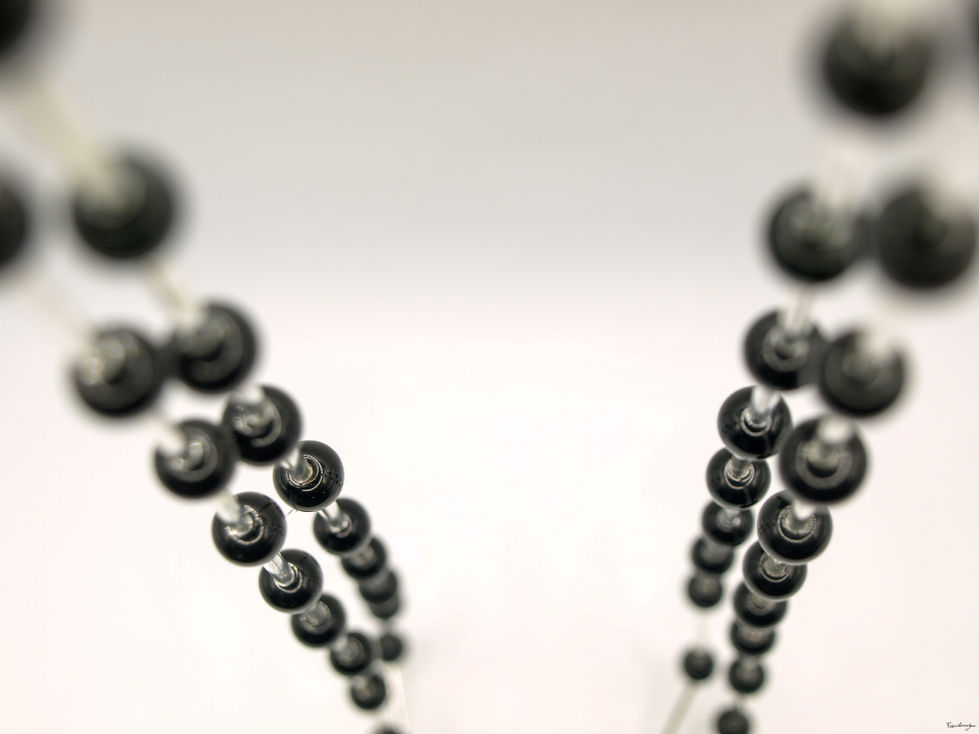 Due collane lunghe uguali, accoppiate, con perle rotonde di ematite, intervallate con fini cristalli cilindrici, argentei, di Swarovski.