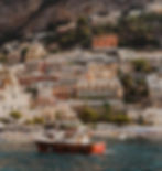 boat floating off the Amalfi coast with colorful building in the background