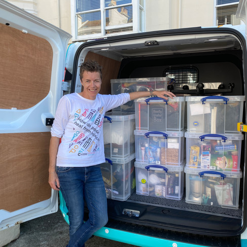 Nina standing outside the back of the van which is packed full of boxes and ready to hit the road for the first time