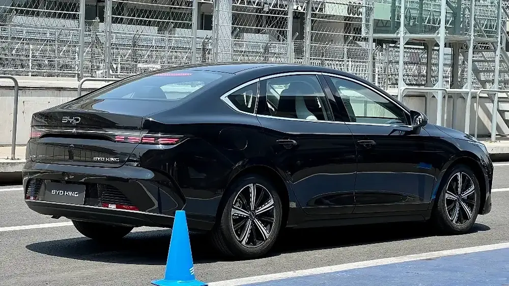 Sedán BYD Han EV negro en pista, cono azul delante.