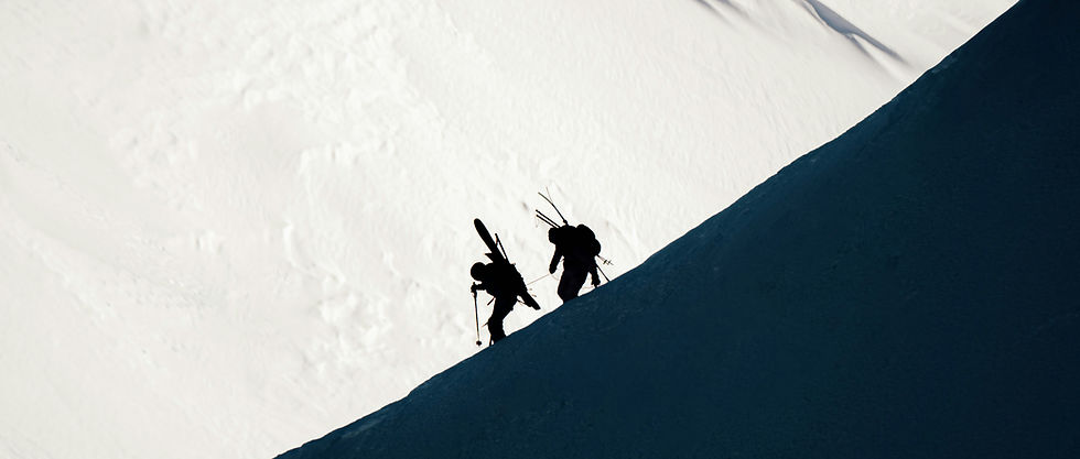 two people climbing a mountain together to snowboard.