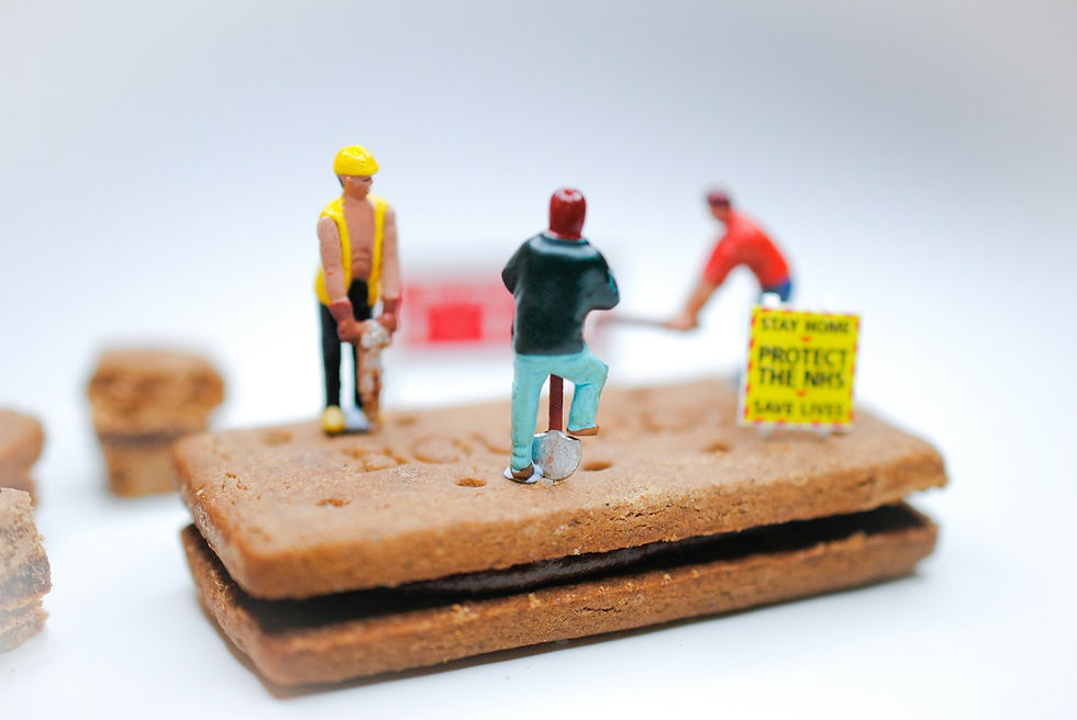 A tiny figurine standing on a construction site built from stacked biscuits