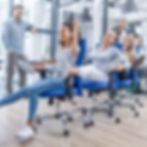 group of coworkers forming a train with a series of office chairs