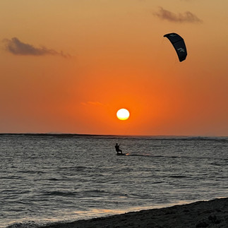 Kleurrijke kitesurfer silhouet tegen de oranje gloed van de ondergaande zon