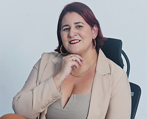 Psicólogo sentada em uma cadeira com a mão no queixo, olhando para seu público com acolhimento.