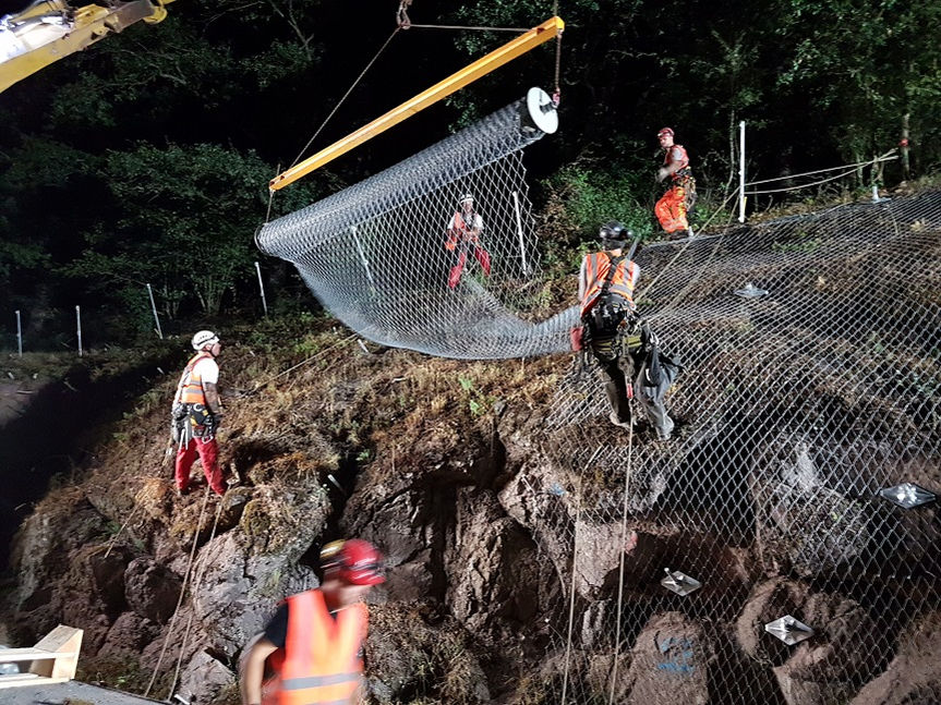 Auf einer Felswand verlegen Mitarbeiter der Jähnig Gmbh ein Steinschlagschutznetz.jpg