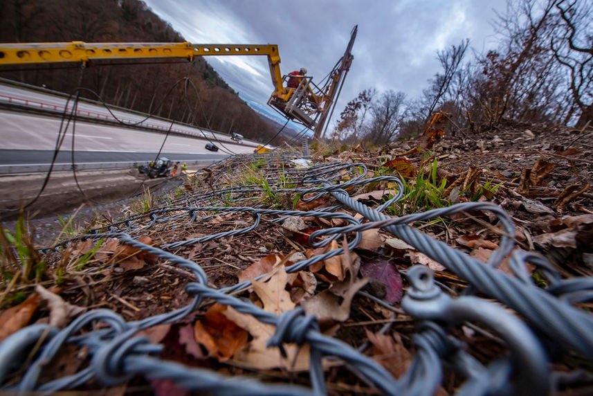 Detailaufnahme eines Steinschlagschutznetzes an der BAB A8. Im Hintergrund bohrt die Jähnig GmbH.