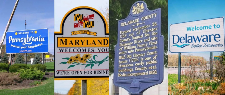 Four roadside welcome signs for Pennsylvania, Maryland, Delaware County, and Delaware against a blue sky.