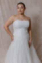 Model wearing plus size couture vintage wedding dress against beige backdrop