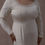 Thumbnail: Plus size model wearing a mid-size couture vintage wedding gown with embellished neckline against a beige backdrop