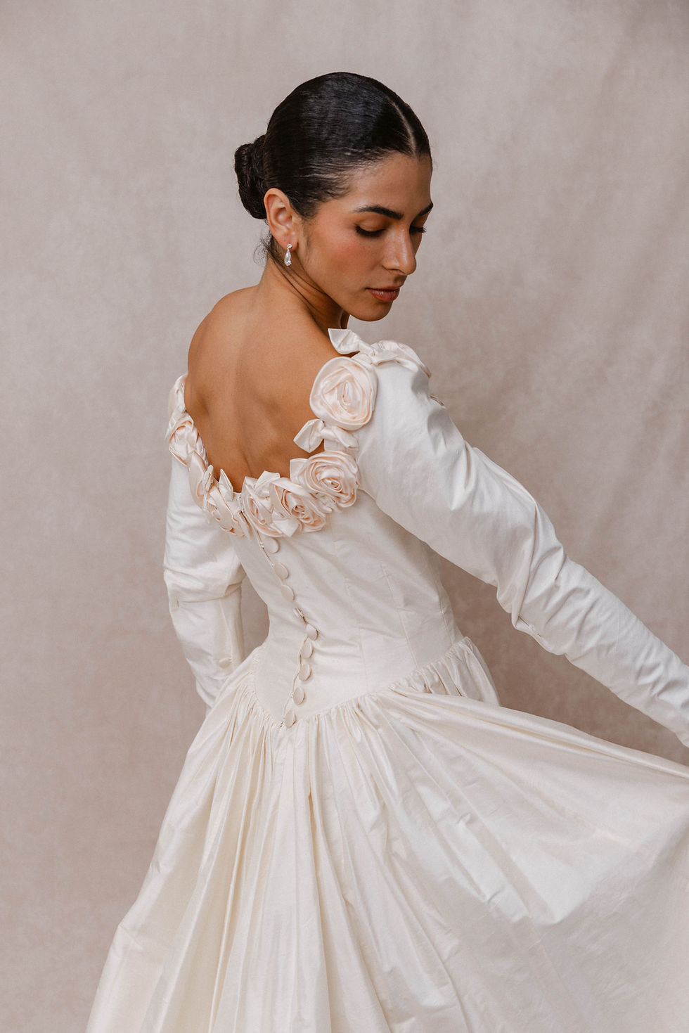 Thumbnail: Bride showing back bodice of vintage Catherine Rayner wedding dress in Atlanta bridal shop