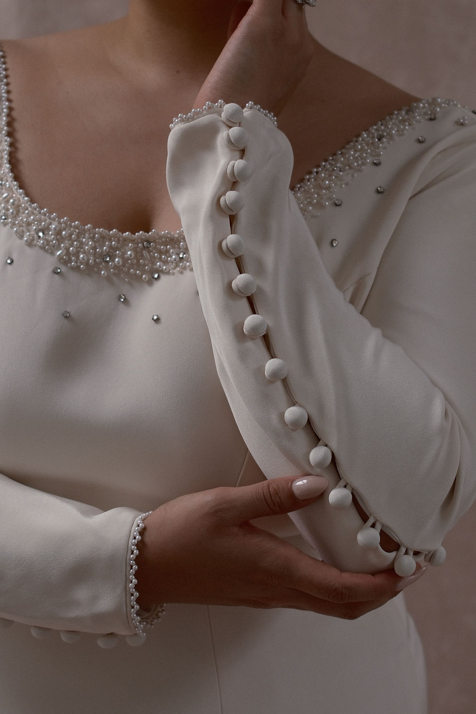 Thumbnail: Plus size model wearing a mid-size couture vintage wedding gown with embellished neckline against a beige backdrop